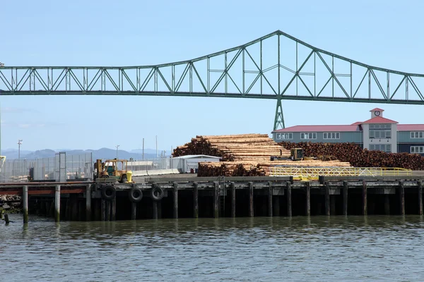 Pile of logs on decks & the Astoria bridge, OR. — Stock Photo, Image