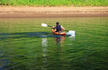 Paddling a kayak in a river. clipart