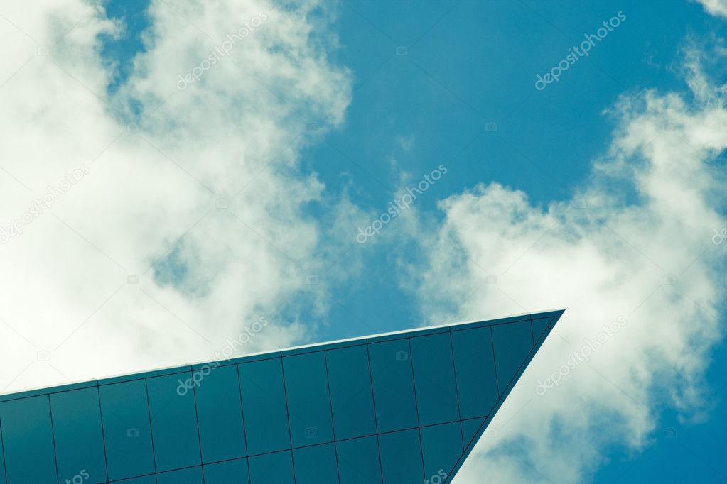 Top of modern corporate glass building with sky and clouds