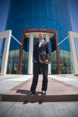 Young lawyer in suit smiling standing outside corporate highrise clipart