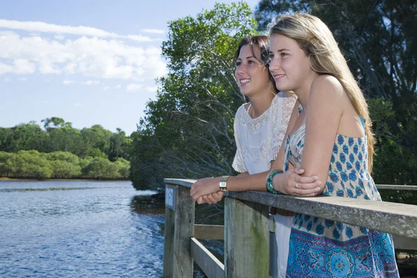 Две девушки, выглядывающие со смотровой площадки у ручья — стоковое фото