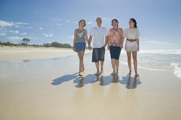 Familia caminando en la playa tomados de la mano — Foto de Stock