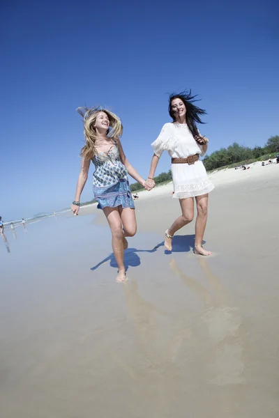 Two sisters running on beach holding hands — Stock Photo, Image