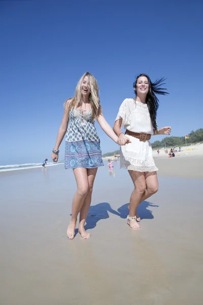 Two sisters running on beach holding hands — Stock Photo, Image