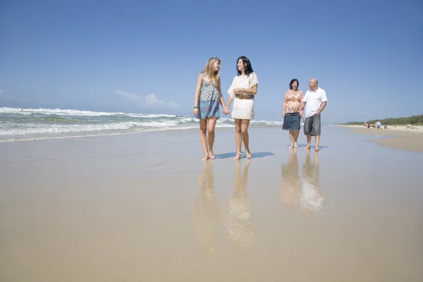 Familia caminando en la playa tomados de la mano — Foto de Stock