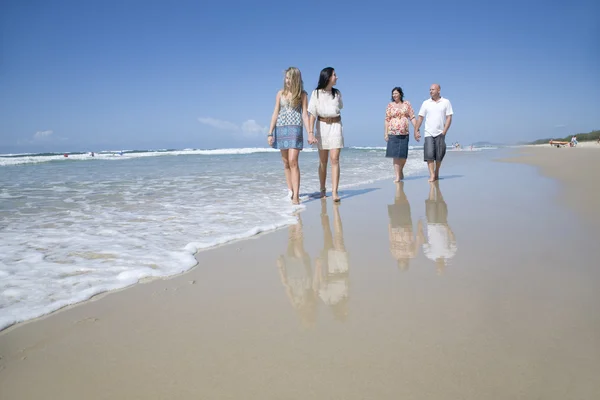 Семья ходит по пляжу держа руки — стоковое фото