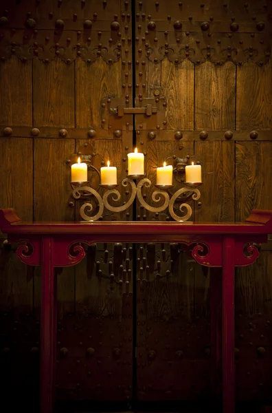 Velas queimando na mesa na frente da velha porta rústica — Fotografia de Stock