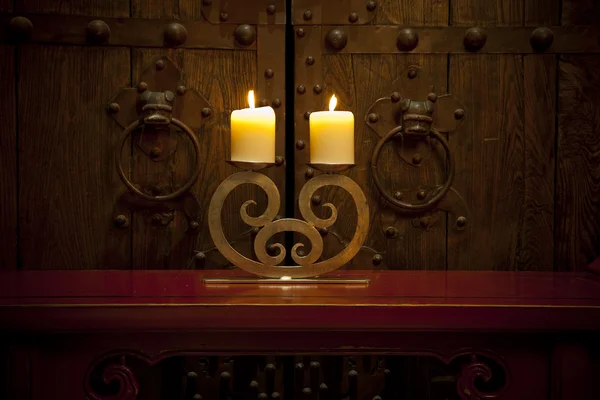 stock image Candles burning on table in front of old rustic door