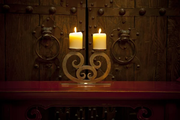 Candles burning on table in front of old rustic door — Stock Photo, Image