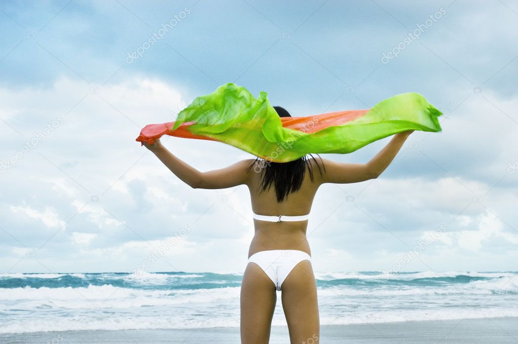 Model on beach in bikini holding shawl in the wind