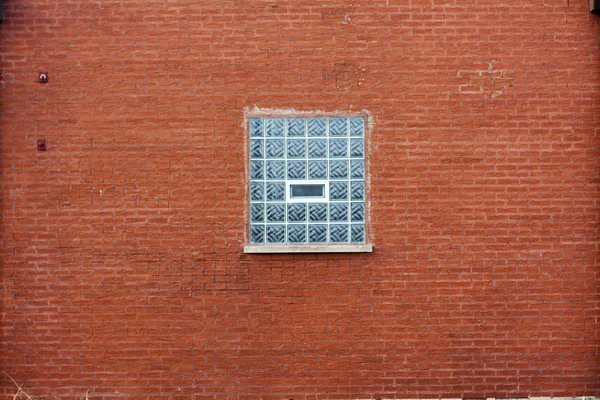 Parede de tijolo vermelho industrial com janela de bloco de vidro azul — Fotografia de Stock