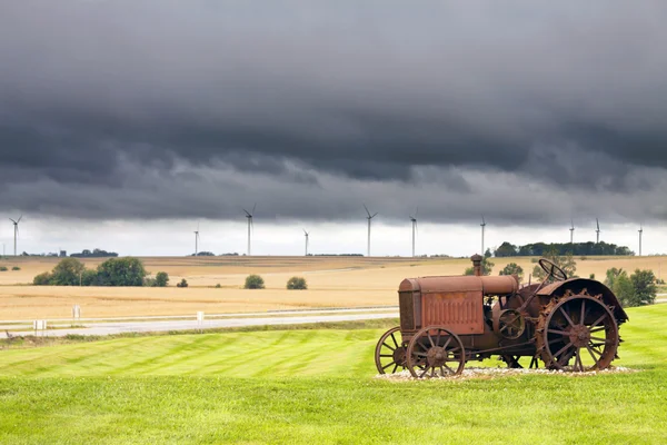 旧生锈拖拉机的暴风雨天气在背景中 — 图库照片