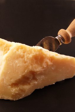 parmesan peyniri siyah bir arka plan üzerinde bir bıçak ile natürmort