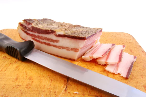 Knife with slices of bacon on a chopping board — Stock Photo, Image