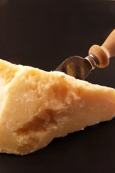 stock image Still life of parmesan cheese with a knife on a black background