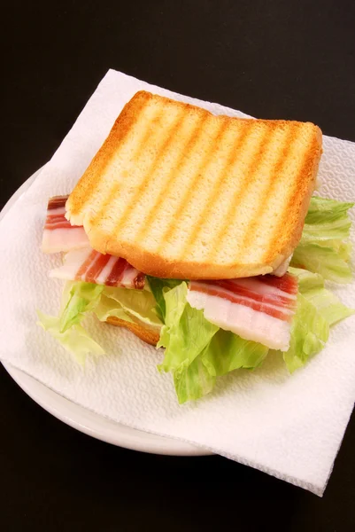 Le pain grillé au bacon, au fromage et à la salade est préparé sur une ba noire — Photo