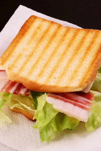 Pâine prăjită cu șuncă, brânză și salată pe un fundal negru — Fotografie, imagine de stoc