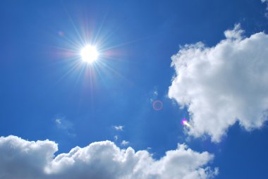 Bright sun with blue skies and clouds clipart