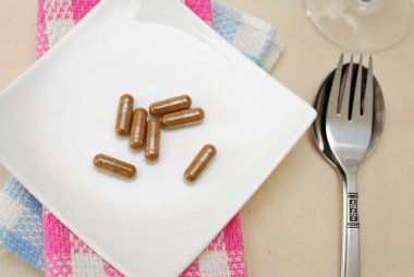 Medicine capsules on dining plate clipart