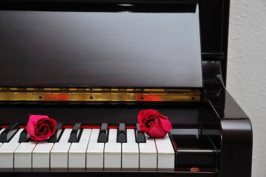 Two red roses on piano keyboard clipart