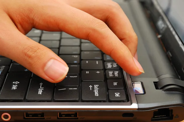 Palcem naciskając przycisk zasilania na laptopie — Zdjęcie stockowe