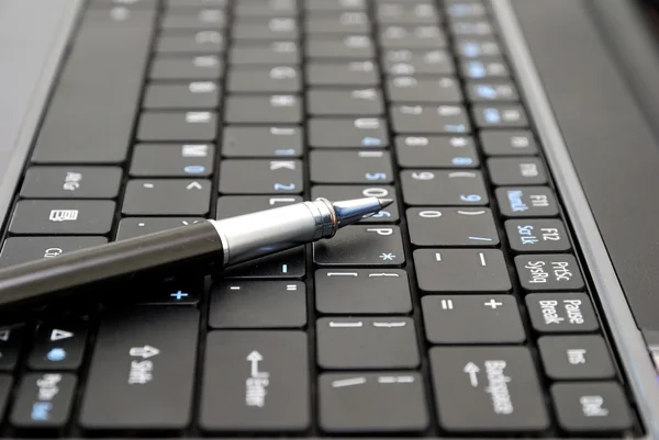 Pluma en el teclado portátil negro — Foto de Stock