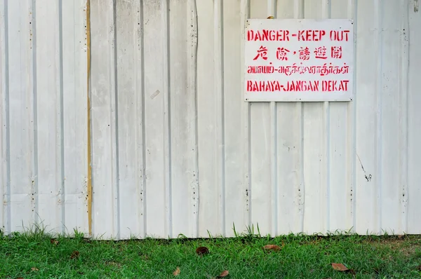 Sinalização de perigo na cerca branca — Fotografia de Stock