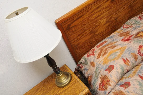 Боковая настольная лампа с кроватью — стоковое фото