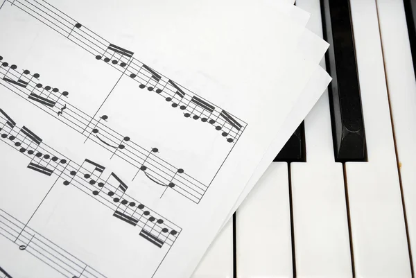 ピアノの鍵盤上の複数の音楽スコア シート — ストック写真