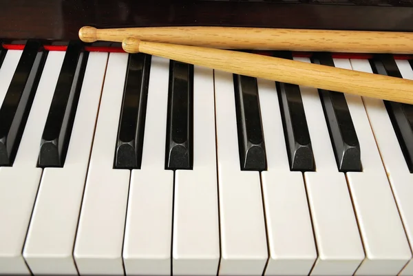 Bâtons de batterie sur clavier piano — Photo