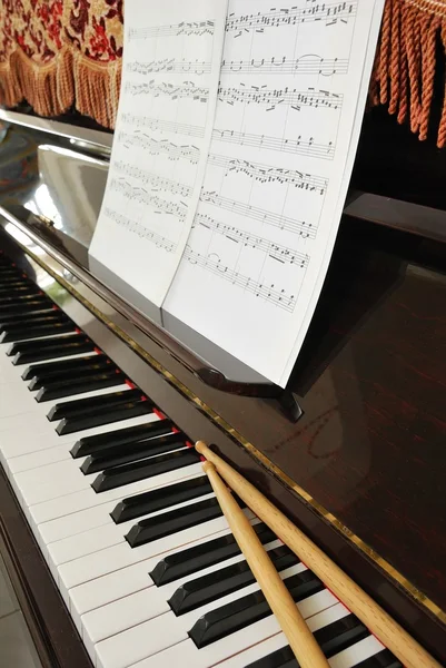 Música partitura e bastões de bateria no teclado de piano — Fotografia de Stock