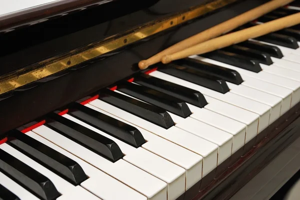 Діагональний знімок барабанних паличок на клавіатурі піаніно — стокове фото