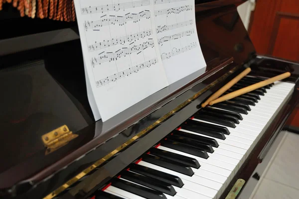 Musik poäng och trumma pinnar på piano keyboard — Stockfoto