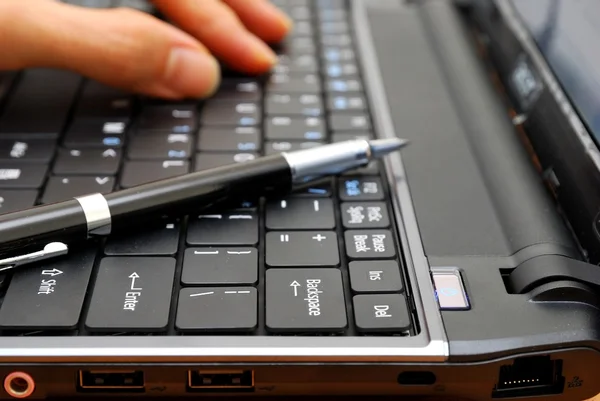 Hand typing on laptop with pen — Stock Photo, Image