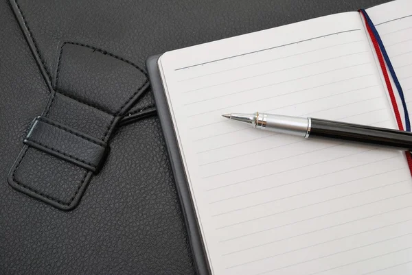 Bolígrafo negro en bloc de notas con maleta — Foto de Stock