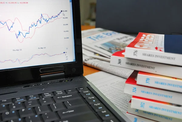 Finanzbücher mit Grafik auf Laptop — Stockfoto