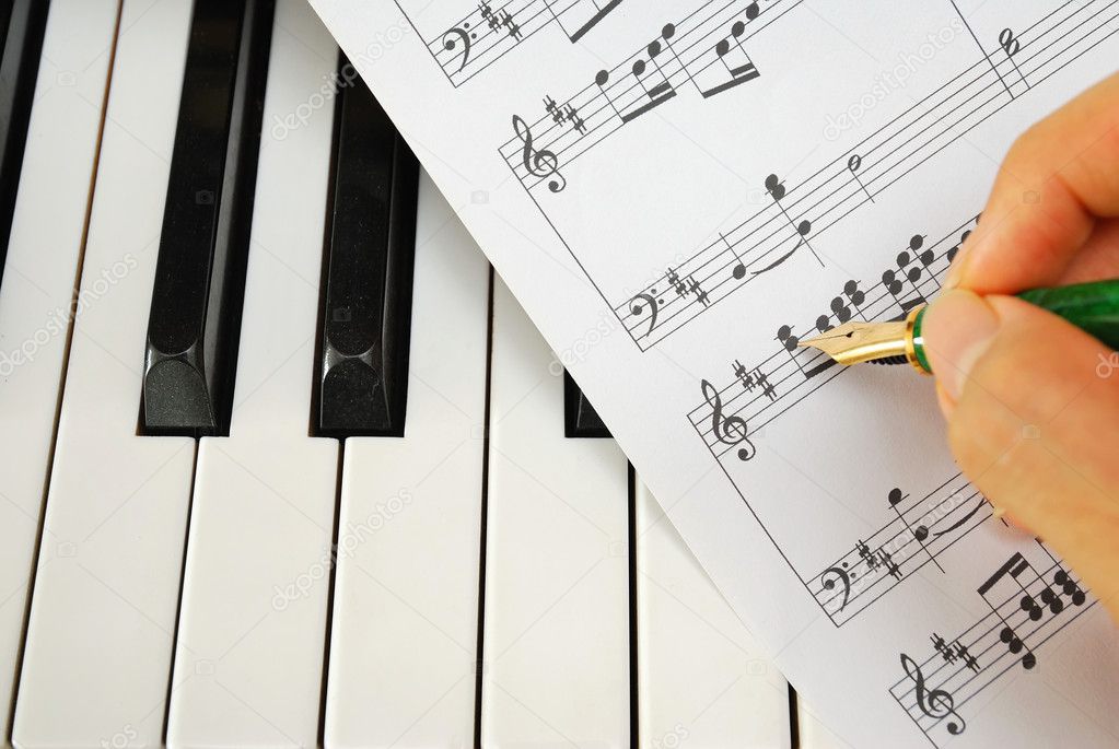Writing on music score with pen on piano keyboard