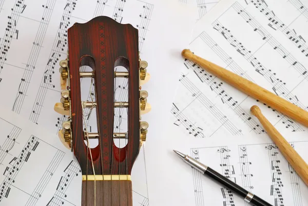Гитара, барабанные палочки с ручкой на музыку — стоковое фото