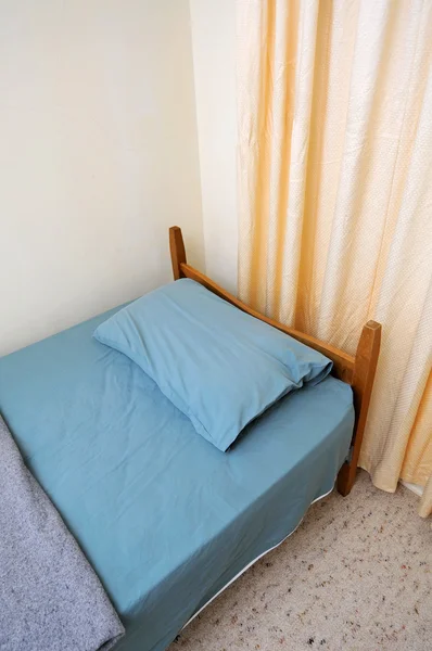Cama individual genérica en habitación de motel — Foto de Stock