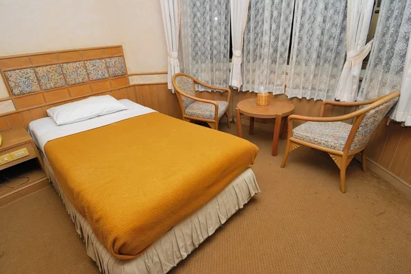 Односпальная кровать в современном номере отеля со столом и стульями — стоковое фото