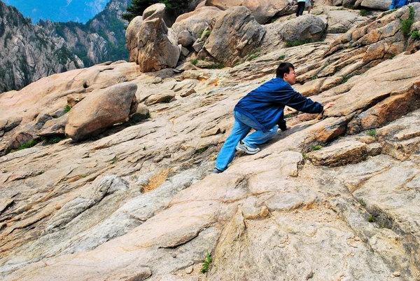 stock image Young man climbing treacherous steep mountain cliff