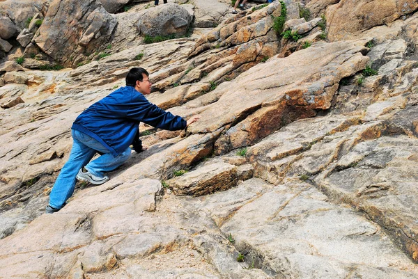 Ung man klättring förrädiska branta berg klippan — Stockfoto