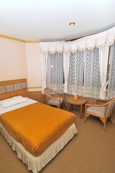 Μονό κρεβάτι σε δωμάτιο ξενοδοχείο με τραπέζι και καρέκλες — Φωτογραφία Αρχείου