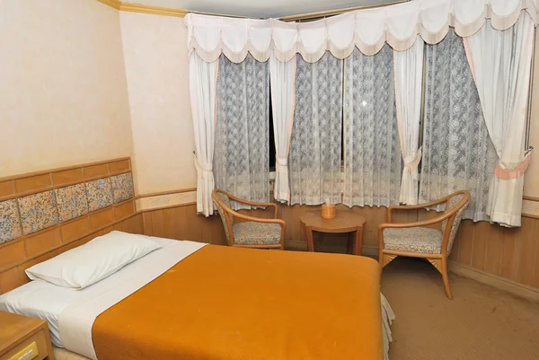 Einzelbett im modernen Hotelzimmer mit Tisch und Stühlen — Stockfoto