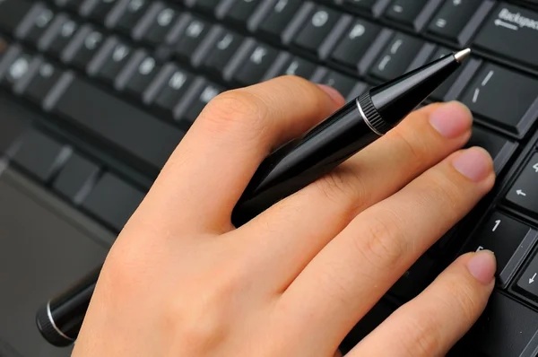 Hand holding pen and typing — Stock Photo, Image