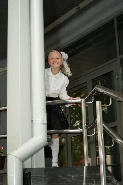 Schoolmeisje staande in de buurt van houvast — Stockfoto