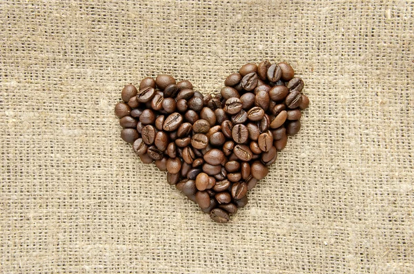 Сердце с кофейными зернами на мешковине — стоковое фото