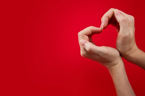 Mãos como coração contra fundo vermelho — Fotografia de Stock