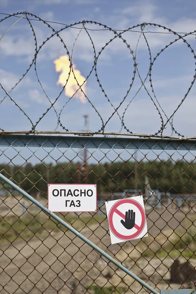 Gas flare behind fence — Stock Photo, Image