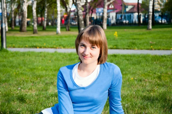 Smiling girl sitting in the park — Stock Photo, Image